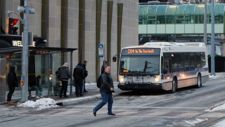 A city bus approaches a crowded bus stop.