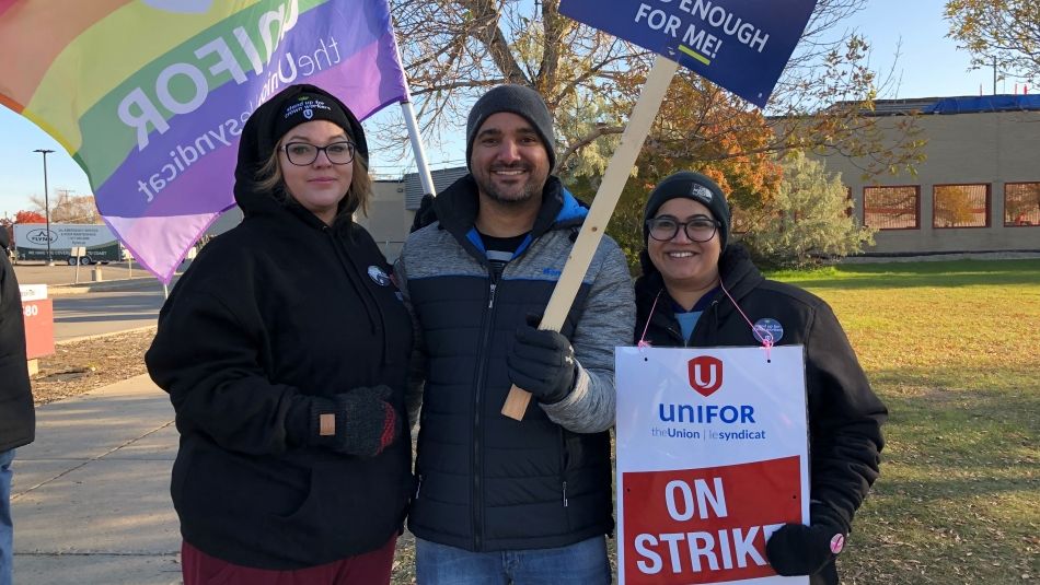 Three unifor members hold flags and signs.