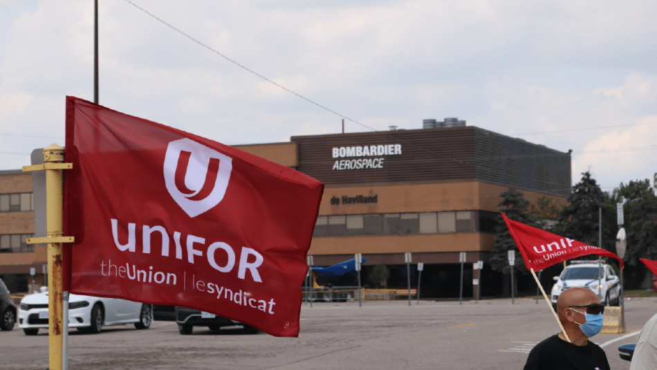 Unifor flag blows in wing in front of building witg Bombardier sign
