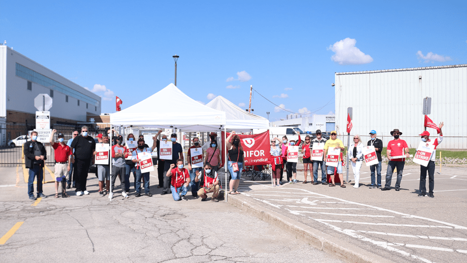 Unifor members holding strike signs and flags on a picket line at Downsview.