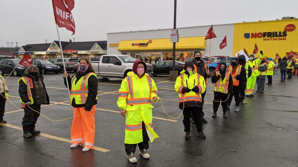 Striking members of Unifor Local 597 form a human solidarity chain.