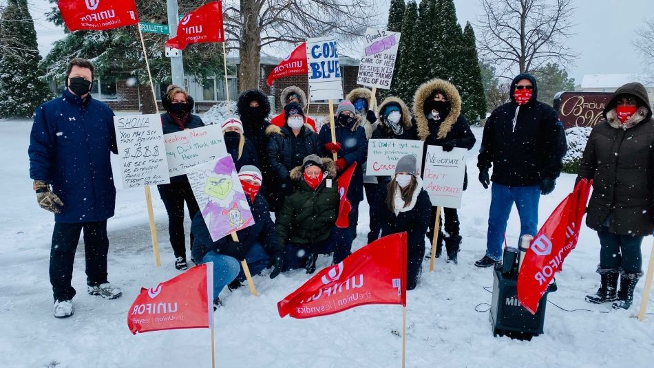 Members of Unifor Local 2458 hold signs and flags outside Brouillette Manor.