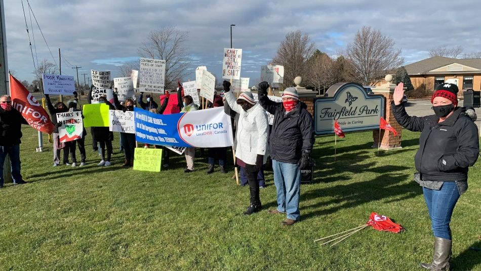 Des membres de la section locale 2458 d'Unifor tiennent des pancartes et des drapeaux à l'extérieur de Fairfield Park..