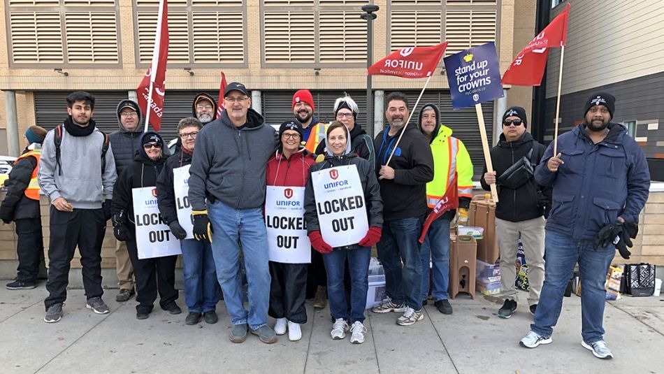Locked-out Unifor members stand on a picket line.