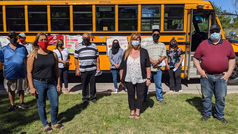 Unifor school bus drivers in front of a school bus.