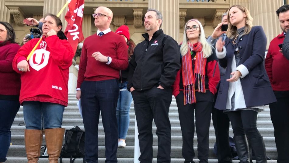 Gavin McGarrigle stands on the steps of the Alberta legislature with other labour activists.