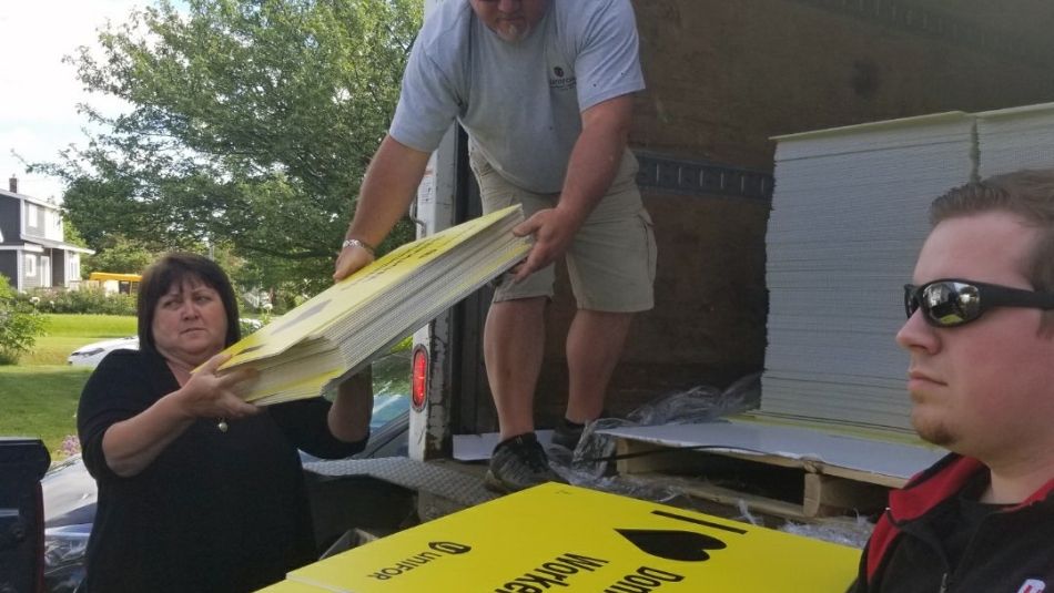 Members of Unifor Local 597 unload signs from a truck.