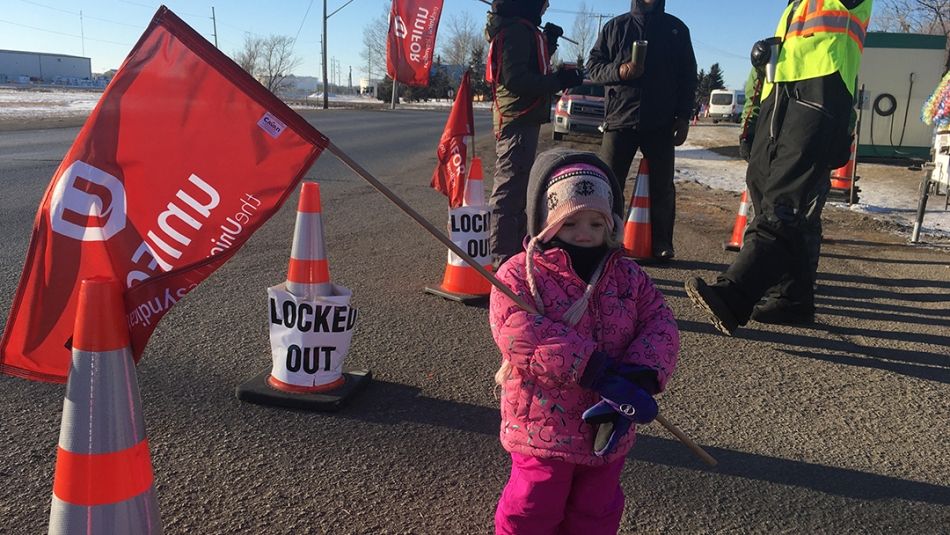 A young child holds a Unifor flag on the picket line at Co-op Refinery.
