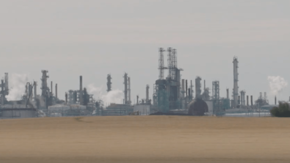 A large oil refinery sits in the distance.