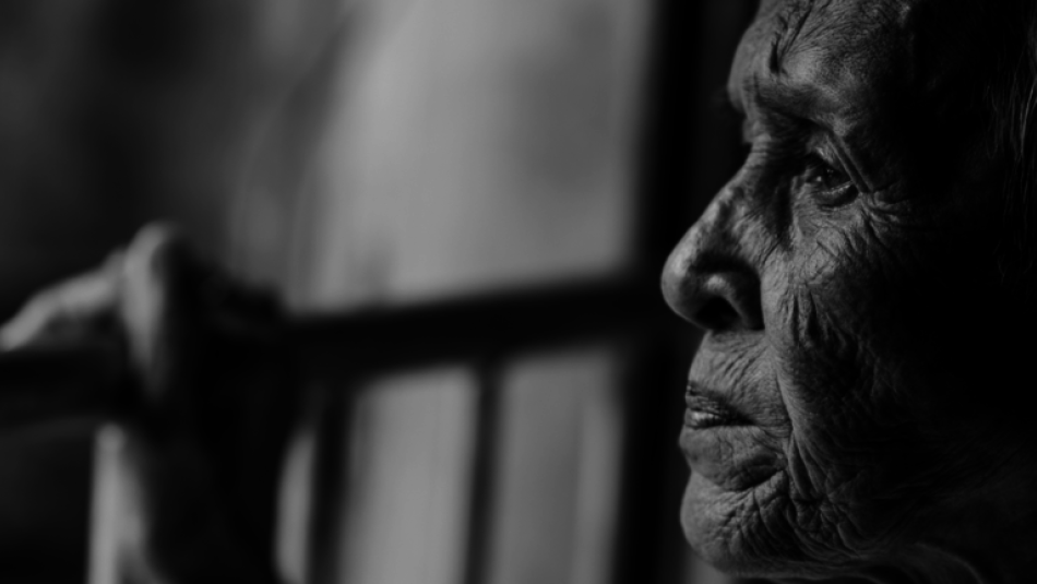 A older women looking out off a balcony with her hand on the railing.