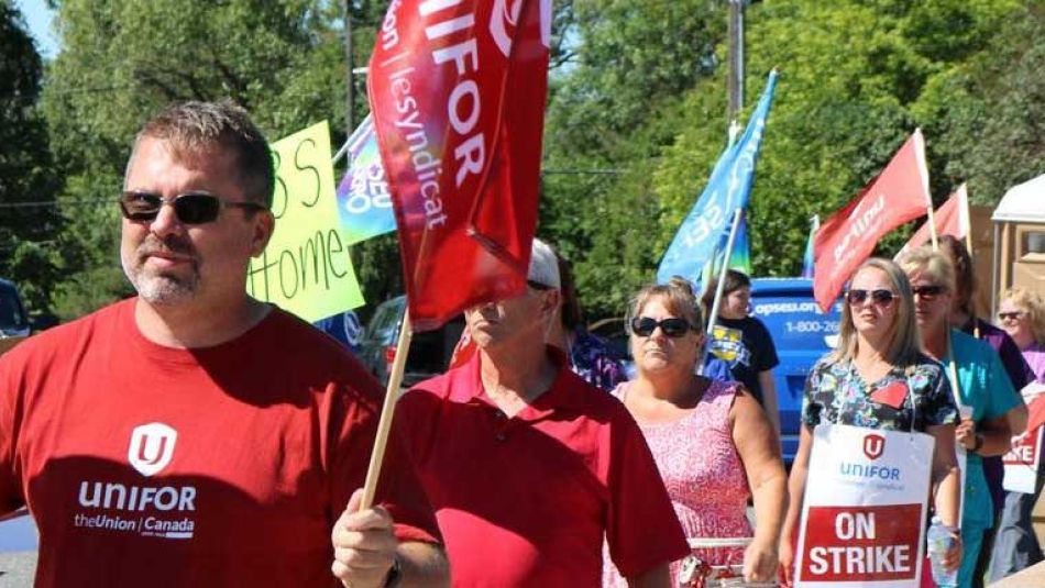 Des membres d'Unifor marchent sur un piquet de grève.