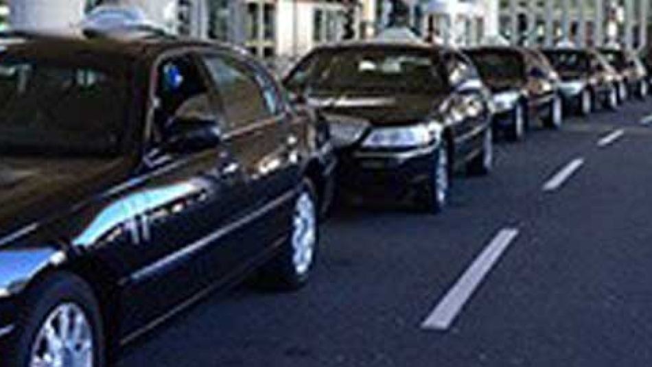 A line of black town cars waits for passengers. 