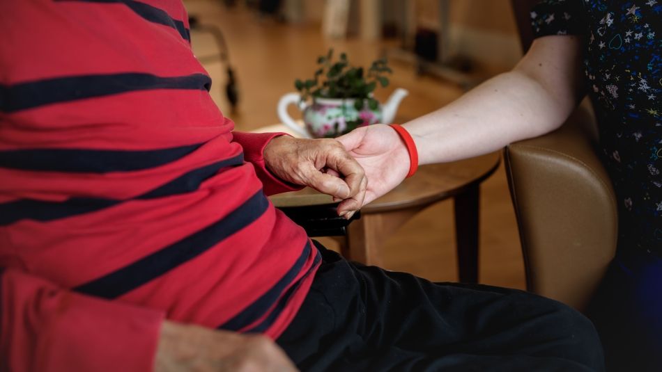 Un résident en soins de longue durée tient la main d'un travailleur de la santé.