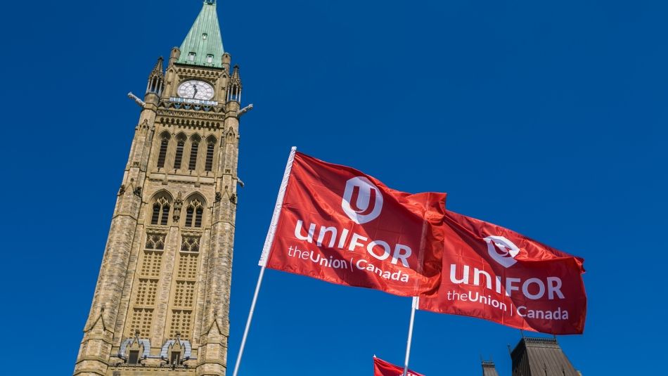 Two Unifor flags fly in front of the Peace Tower in Ottawa, Ontario.