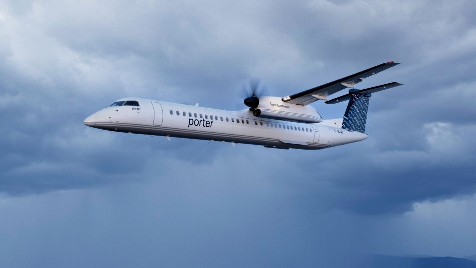 A Porter airlines plane flies through a cloudy sky.