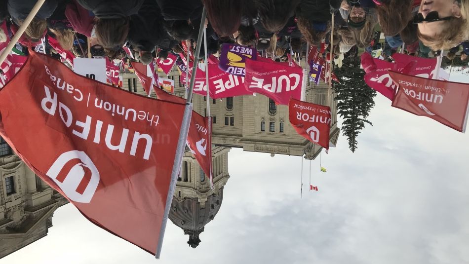 A crowd of Union activists wave flags in front of the Saskatchewan legislature.