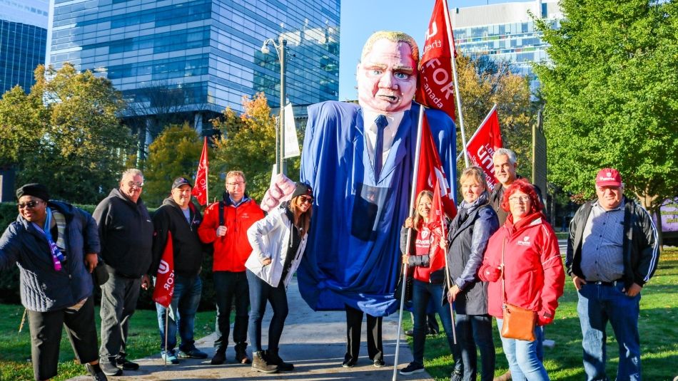 Unifor activists pose with a giant Doug Ford puppet.