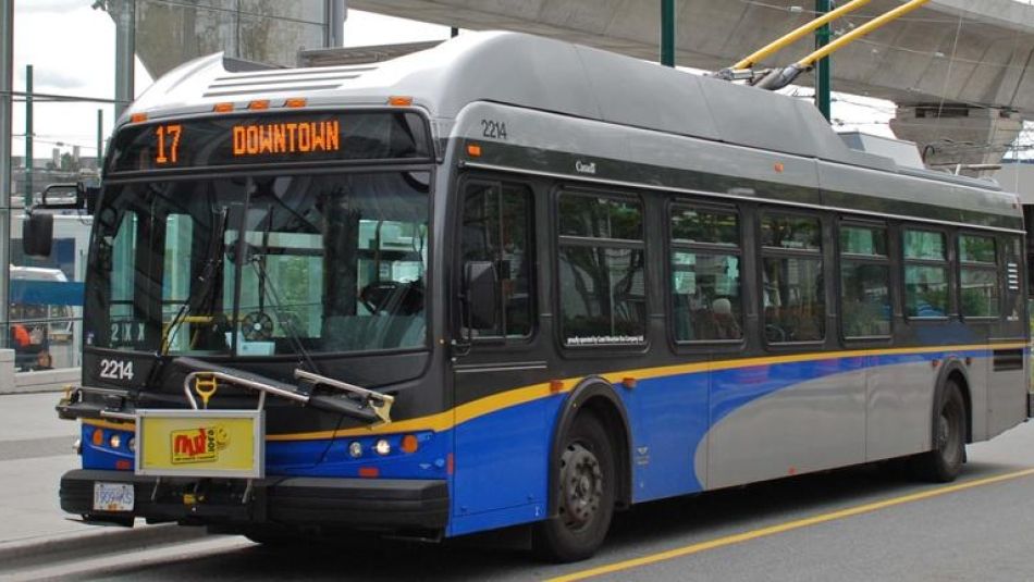 A city bus waits at a bus stop.