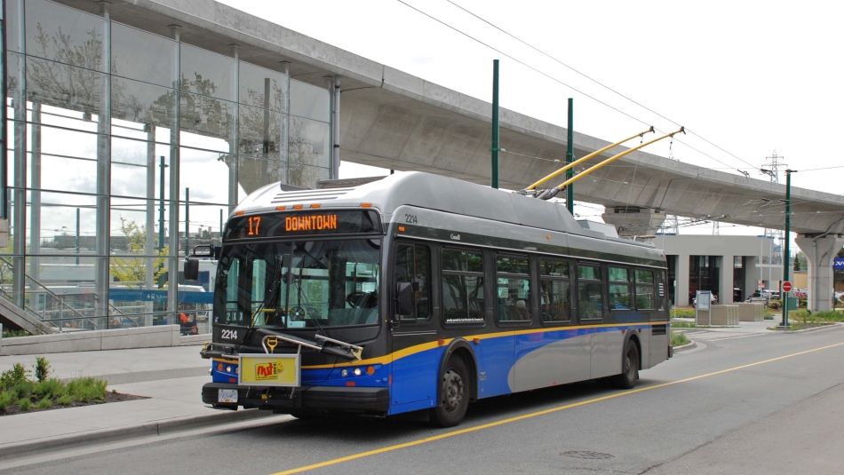 A city bus waits at a bus stop.