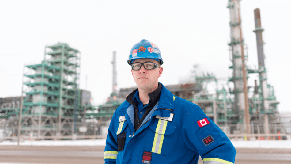Worker in overalls and hard hat standing outside of a refinery