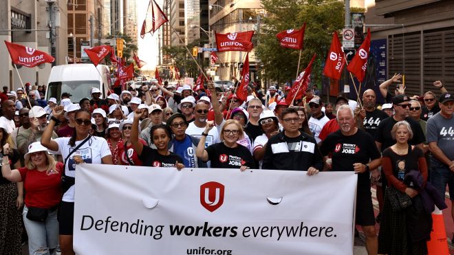 Lana Payne leads a contingent of Unifor members down a busy downtown Toronto street.
