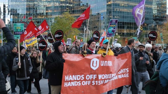 Rally for $15 for fairness goup holding a unifor banner