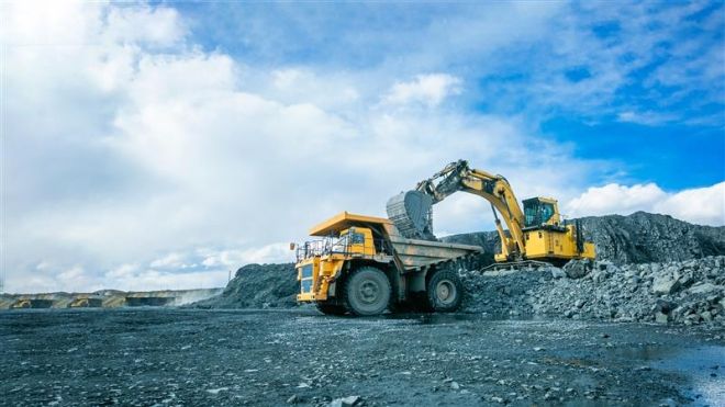 industrial excavator loading a dump truck outdoors in a grey rocky landscape