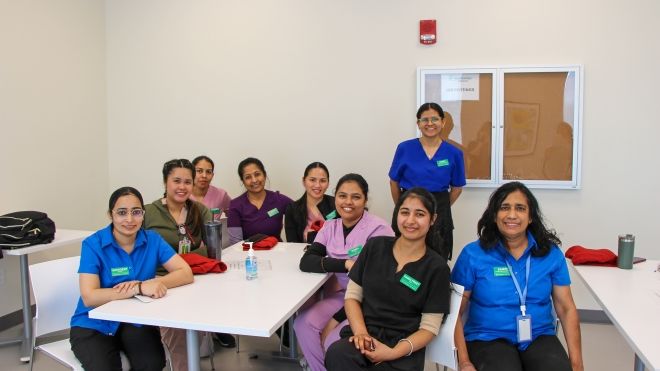 A small group of long term care workers smile brightly while holding Unifor t-shirts. 