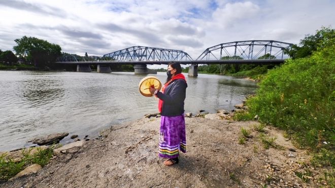 Woman at riverbed holding drum