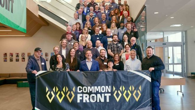 A group of dozens of union leaders posed on a staircase with a banner reading Common Front.
