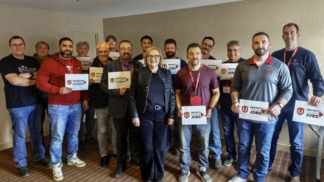 A group of workers standing with Lana Payne holding signs saying "Protect Canadian Jobs".