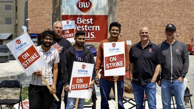 Six people pose in front of Best Western signage holding On Strike signs