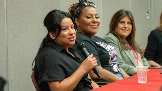 Three women sitting at a table one is speaking into a mic