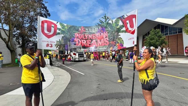 Two people holding up a banner with festival attendees in the background