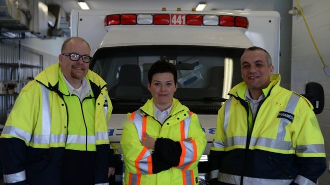 3 paramedics standing infront of an ambulance