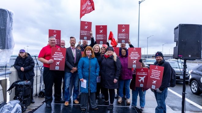 A group of people holding red signs and red Unifor flags.