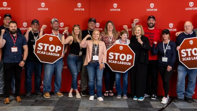 A group of people with several holding Stop Scab Labour signs