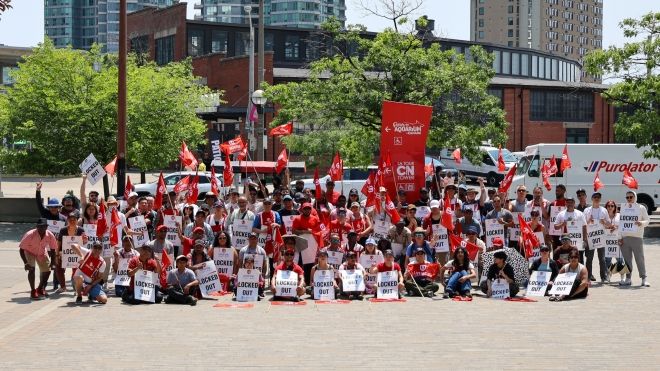 A large group photo of members with locked out placcards and red Unifor flags and shirts