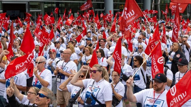 A group of people holding flags and wearing Protect Canadian Jobs! shirts.