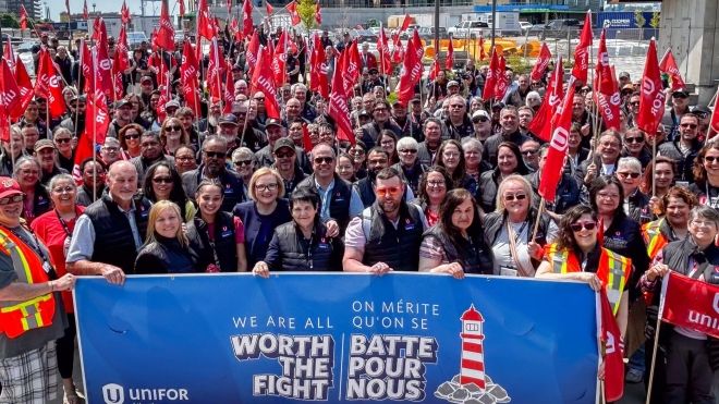 A large crowd at a rally behind a large banner that reads, Worth the Fight!