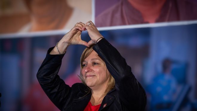 Jenn Murray making a heart shape with her hand overhead 