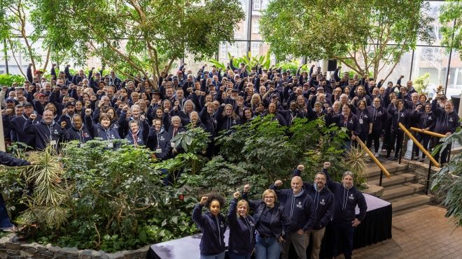 A large goup fists raised wearing black Unifor sweaters