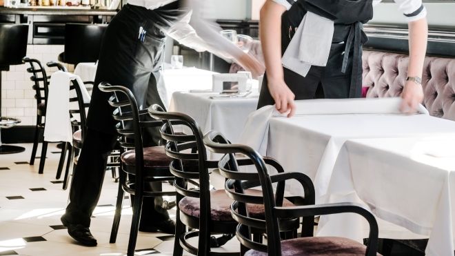 Waiters setting up tables with clean white linens 