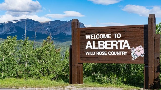 Wooden signage outdoors reading Welcome to Alberta: Wildrose country