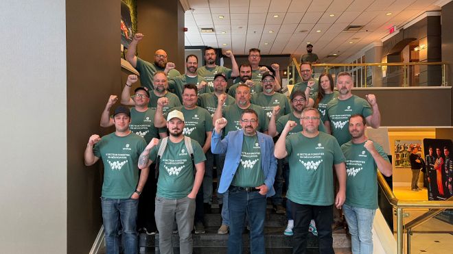 A large group in green shirts posing on a staircase