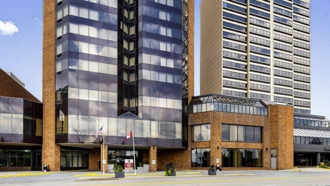 Exterior of a glass tower building from street level. Only first dozen floors are visible