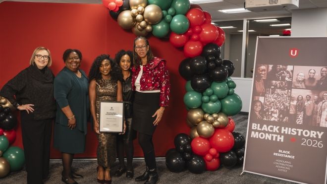 Five people stand beside a baloon arc in front of a red backdrop