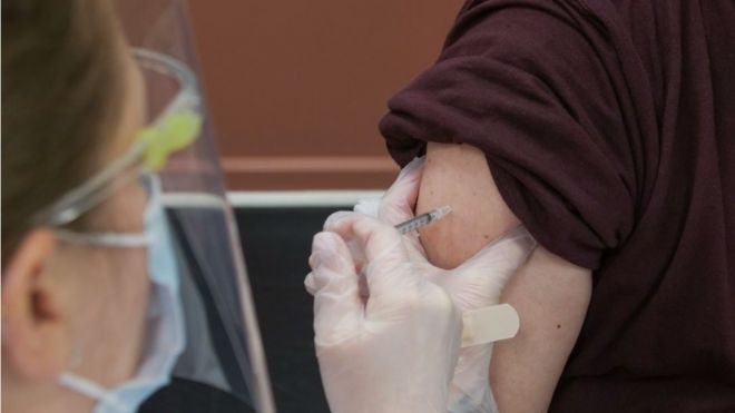 Agent de santé en EPI donnant un vaccin