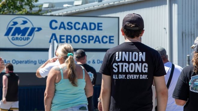 Unifor members walking on the picket line in front of a sign that reads Cascade Aerospace
