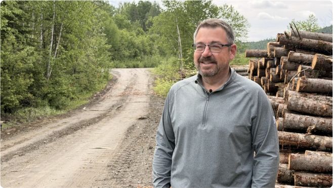 A man standing along side a forested road.